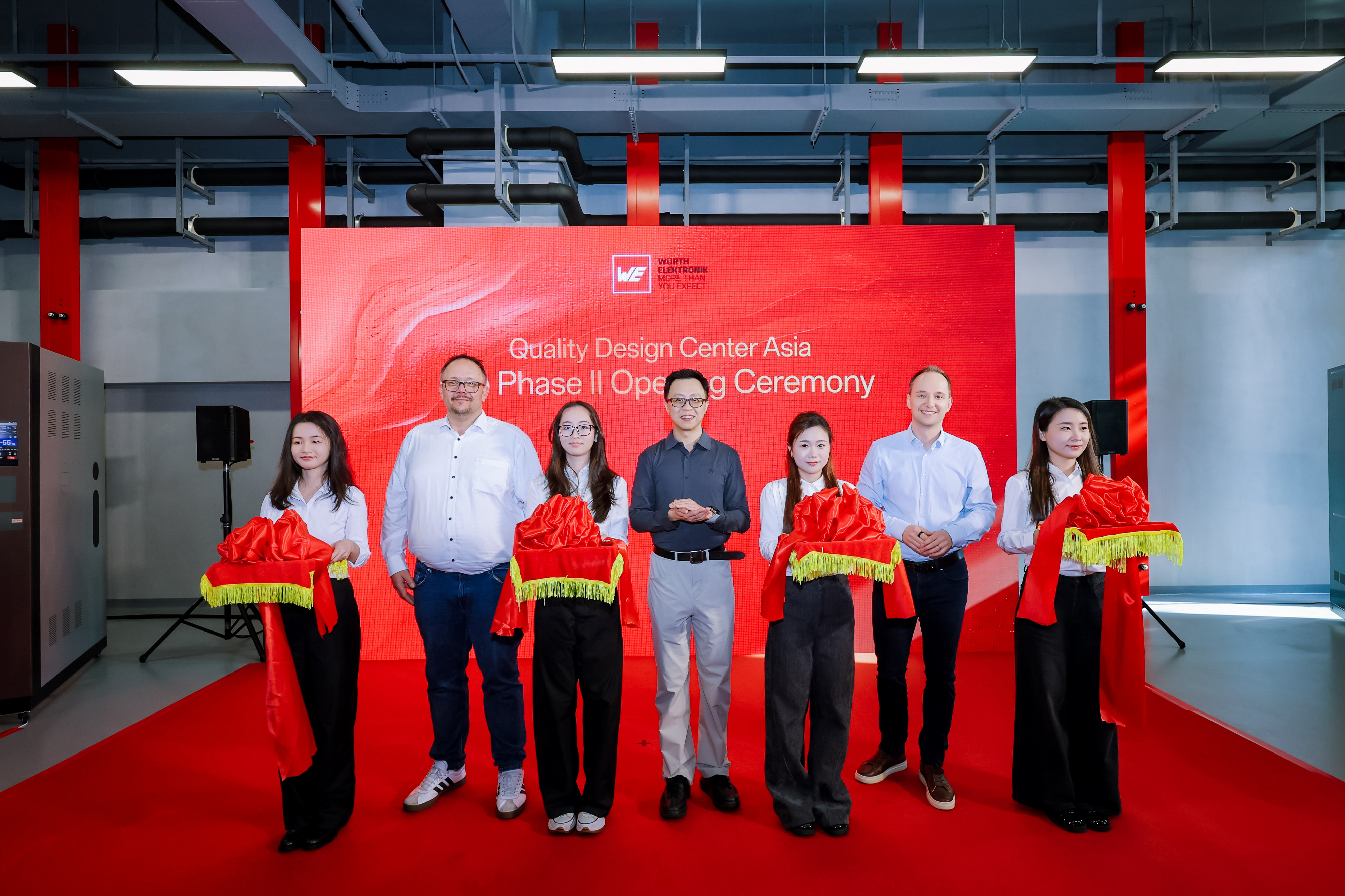 Stolz auf die Eröffnung der neuen Prüfeinrichtungen in Shenzhen (China) der Würth Elektronik eiSos Gruppe: Dirk Knorr, COO, Yangyang Chen, Leiter des QDC Asia, und Thomas Garz, CEO, in Begleitung von Mitarbeiterinnen des QDC (von links nach rechts).